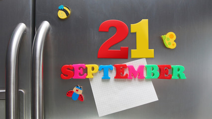 September 21 calendar date made with plastic magnetic letters holding a note of graph paper on door refrigerator