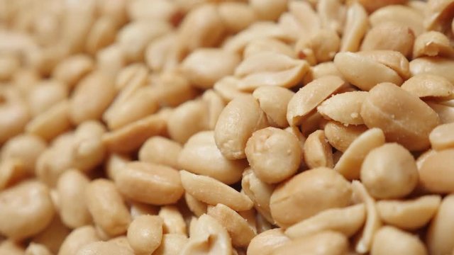 Snack Arachis hypogaea close-up slow tilting food background 4K 2160p UltraHD video - Popular snack roasted and salted groundnut peanuts pile 4K 3840X2160 UHD tilt footage 
