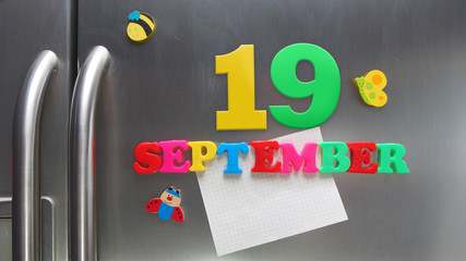 September 19 calendar date made with plastic magnetic letters holding a note of graph paper on door refrigerator