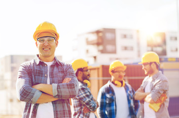 group of smiling builders in hardhats outdoors