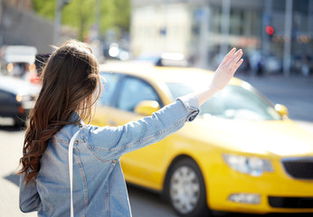 young woman or girl catching taxi on city street