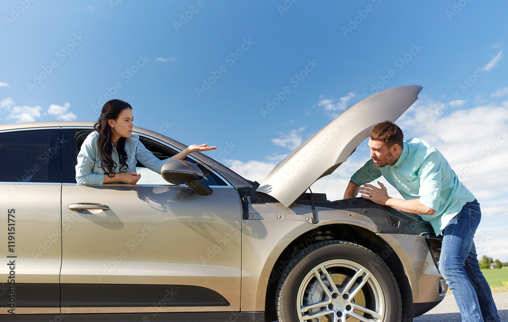 Wall mural couple with open hood of broken car at countryside