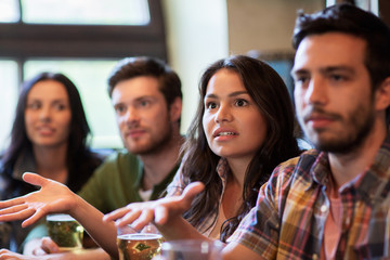 friends with beer watching football at bar or pub