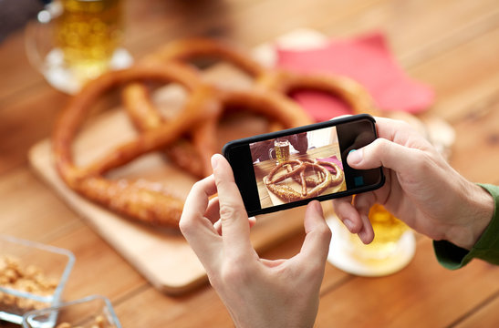 close up of hands picturing pretzel by smartphone