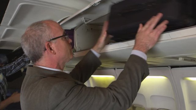 Traveler putting luggage in overhead bin