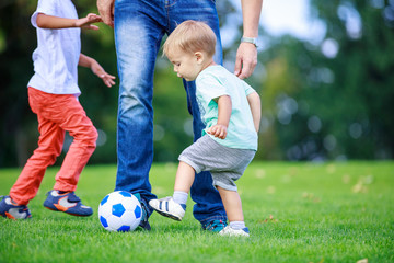 Father and sons playing football in park