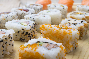 Different Sushi rolls,wasabi and ginger on a plate on wooden bac