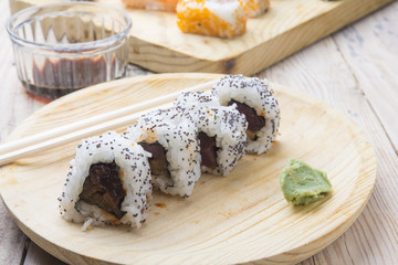 Different Sushi rolls,wasabi and ginger on a plate on wooden bac