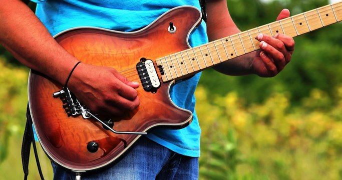 Man In A Light Blue Shirt Playing Guitar Outside