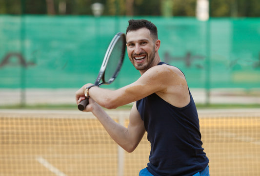 Happy young man playing on tennis clay court.