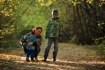 Naklejka na ściany i meble Mother and her children in the autumn forest