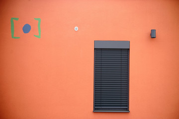 Moderne Hausfassade mit Fenster / Die moderne Fassade eines modernen Wohngebäudes mit einem Metallfenster mit Metalljalousie.