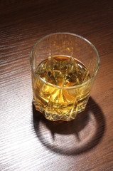 Glass jars with whiskey and ice on wood table