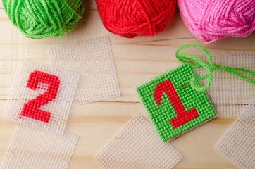 Plastic Canvas, hand made with red yarn number on wooden backgro