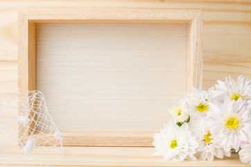 Selective focus of photo frame with flowers on the wooden table