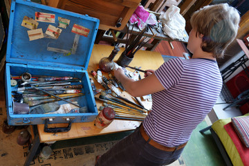 Woman artist paints in her workshop.
