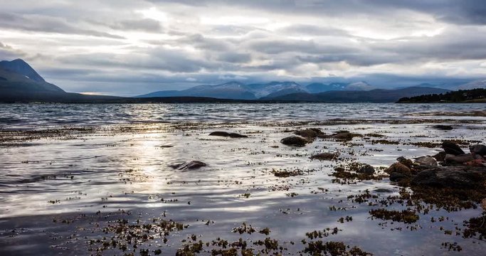 Timelapse of tide and sunbeams over mountain in a fjord