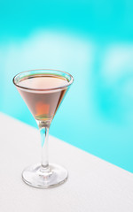 Cocktail on white table in front of swimming pool