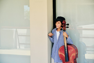 Boy fine tuning large red cello