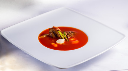 tomato soup with meat in a white plate