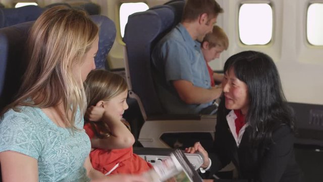 Flight attendant speaking to child on plane