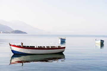 Fishing boats standing still on a beautiful lake in Ohrid, Macedonia, early in the morning with reflection on water