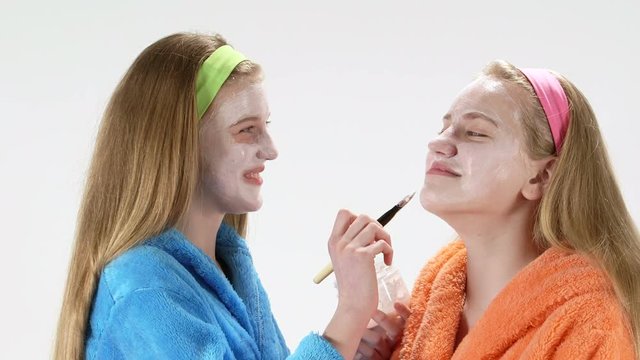 Teen skin care treatment teenage girls having fun together applying each other homemade face cream mask
