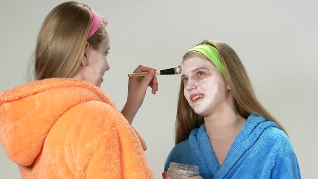 Teenage girls applying homemade face cream mask for teens adding moisture to facial skin 