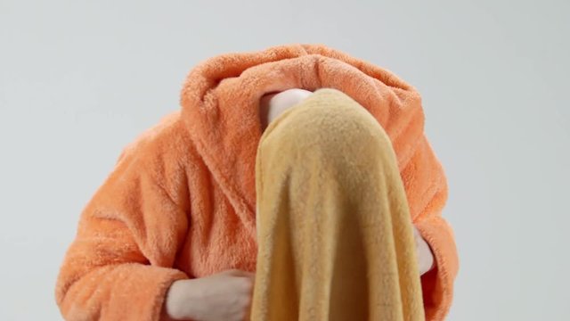 Young girl wearing bathrobe wrapping her wet hair in a towel after a shower