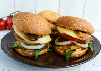 Homemade hamburgers with juicy cutlet, arugula, bacon, vegetables and mozzarella.
