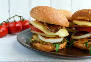 Homemade hamburgers with juicy cutlet, arugula, bacon, vegetables and mozzarella.