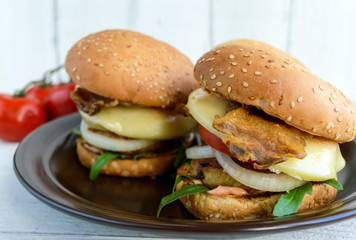 Homemade hamburgers with juicy cutlet, arugula, bacon, vegetables and mozzarella.