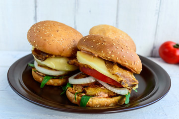 Homemade hamburgers with juicy cutlet, arugula, bacon, vegetables and mozzarella.