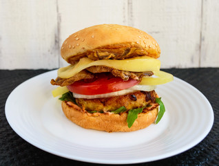 Homemade hamburger with juicy cutlet, arugula, bacon, vegetables and mozzarella.