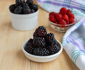 Freshly picked blackberries and raspberries on a light wooden background