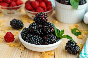 Freshly picked blackberries and raspberries on a light wooden background
