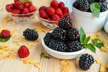 Freshly picked blackberries and raspberries on a light wooden background
