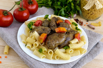 Pasta and fried goose liver (chicken, duck) with pesto and tomato on a white background.