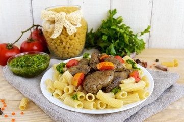 Pasta and fried goose liver (chicken, duck) with pesto and tomato on a white background.