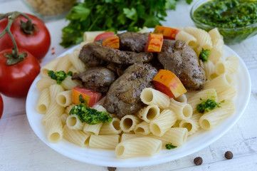 Pasta and fried goose liver (chicken, duck) with pesto and tomato on a white background.
