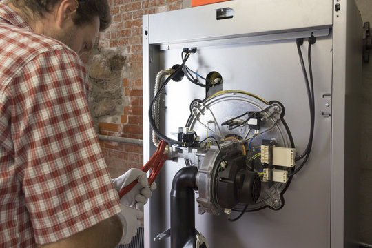 plumber repairing a condensing boiler in the boiler room