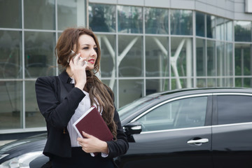 Fototapeta premium Business woman on phone standing in the street background car