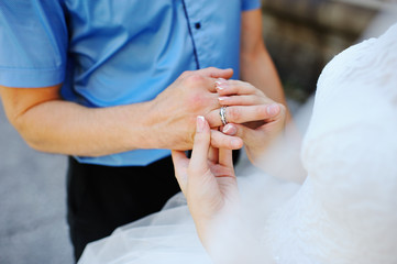 Obraz na płótnie Canvas Bride puts ring made of white gold groom closeup
