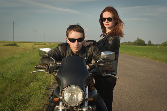 Biker man and girl stands on the road