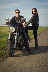 Biker man and girl stands on the road