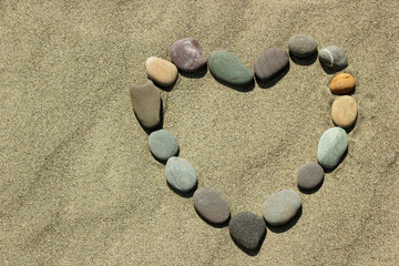 Fototapeta na wymiar Stones in shape of heart on sand background.