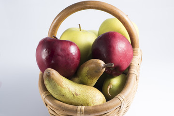 wicker basket full of fruits like pears and apples of different quality.
