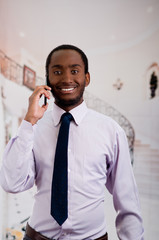 Handsome man wearing shirt and tie standing in lobby area talking on mobile phone, business concept