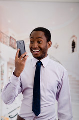 Handsome man wearing shirt and tie holding up mobile phone posing while taking a selfie