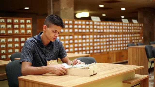 handsome boy  looking on catalog on the tables in a library